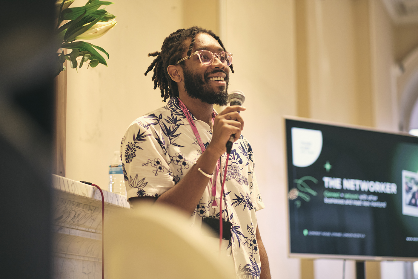 A photo of Akil Benjamin leading a workshop as part of the Black Business Incubator. Akil is Black man with medium length dreads and a beard. He is smiling and holding a microphone.