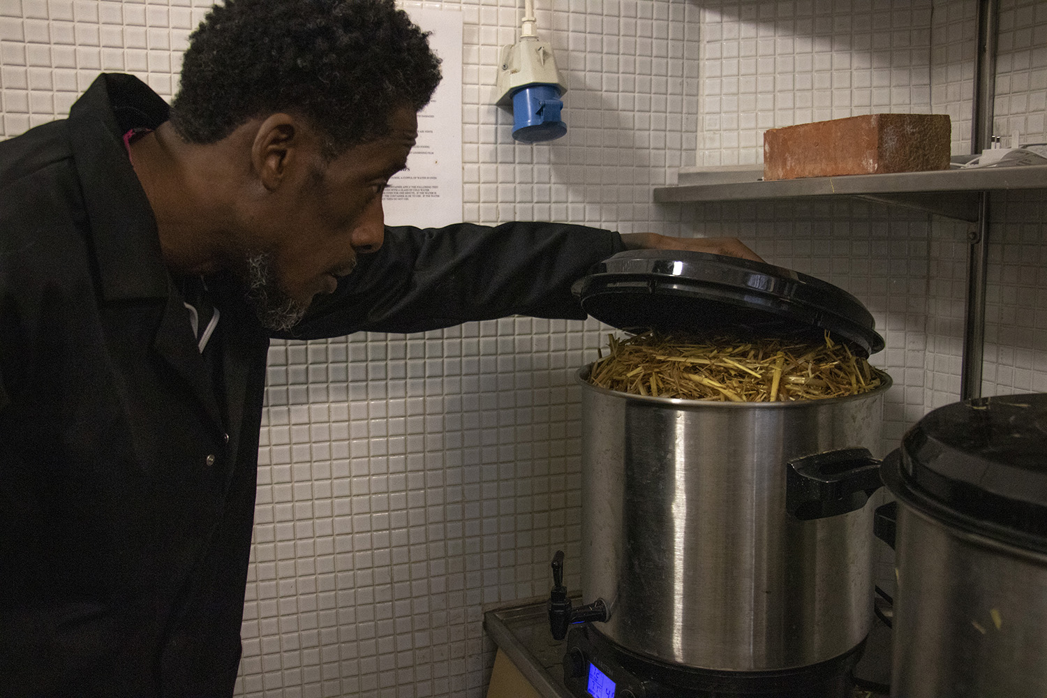 A man looking at a pot of hay that is pasteurising