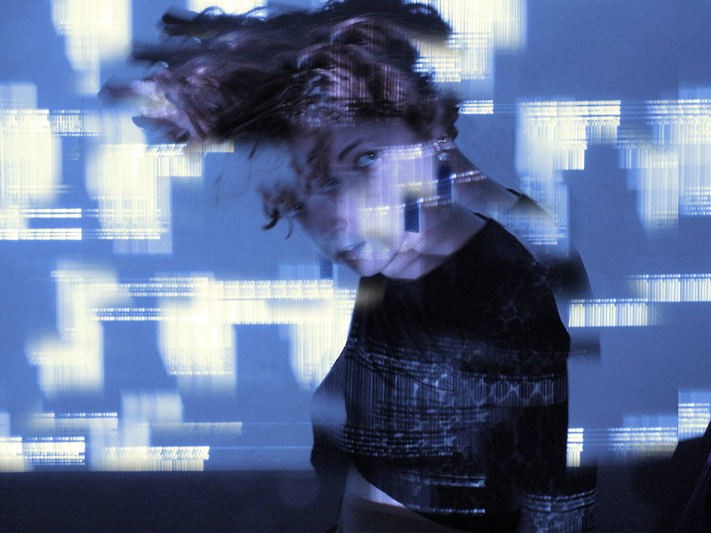 A photo of Flor de Fuego, her head in motion turning toward the camera, with digital glitches projected over her face