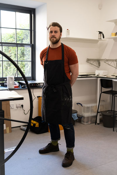 A photo of the artist James Randell wearing an apron in his studio