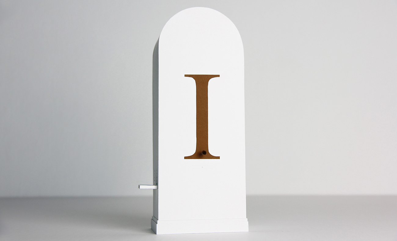 A white plinth stands tall with the letter I'' carved or painted in the middle.