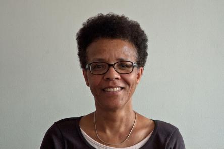 A photo of Gail Lewis. A Black woman wearing glasses with short cropped hair. Gail is looking directly to the camera and has a kind smile.
