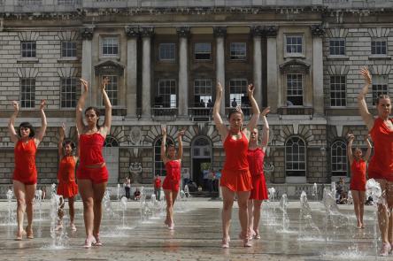 Dancers dressed in red perform amongst the fountains in the courtyard at Somerset House