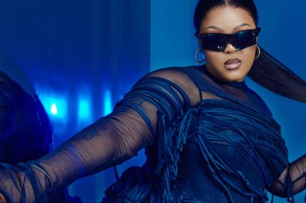 A studio portrait of musician DBN Gogo wearing a blue dress and sunglasses