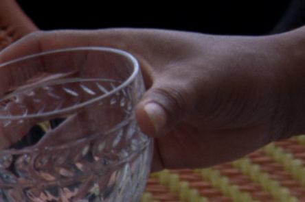 A still from Ana Vaz's Occidente. It shows a hand holding a crystal cut glass.