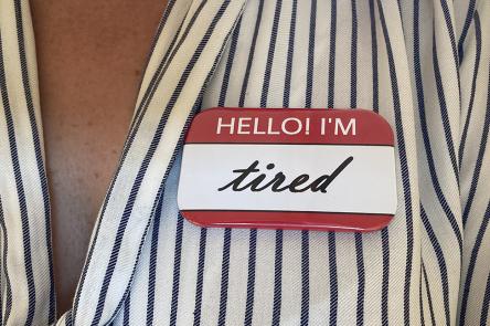 A photo of a person's upper chest, with a sticker on it that reads 'Hello! I'm tired'