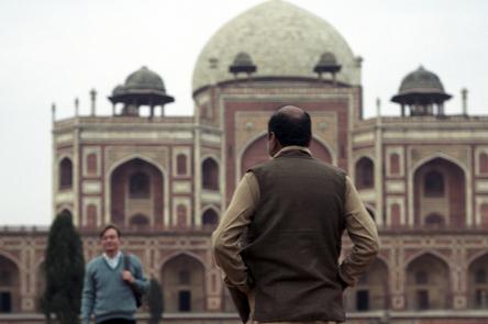 A photo by Sunil Gupta. It shows a man standing infront of a Humayun's Tomb.