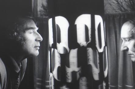 A black and white photo of two men looking at a light installation / dream machine