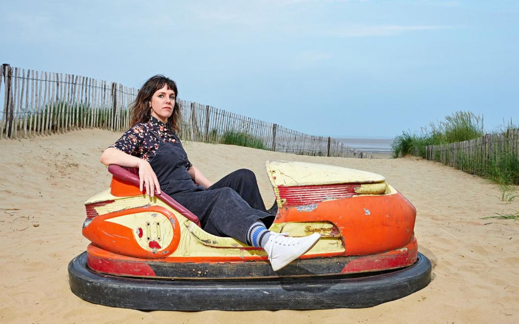 Anna Meredith, Bumps Per Minute album cover shows Anna sitting in a dodgem amongst some sand dunes © Mike Massaro