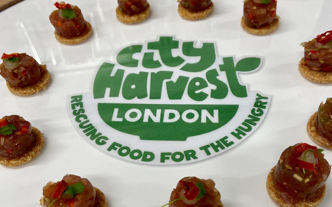 A photo of canaped laid out on a table. In the centre of the table are words that read 'City Harvest London, rescuing food for the hungry'