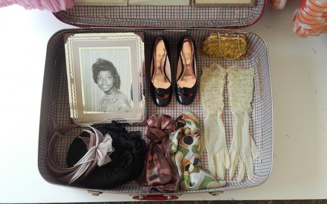 A suitcase containing shoes, clothing accessories and a framed portrait, belonging to a Windrush generation migrant