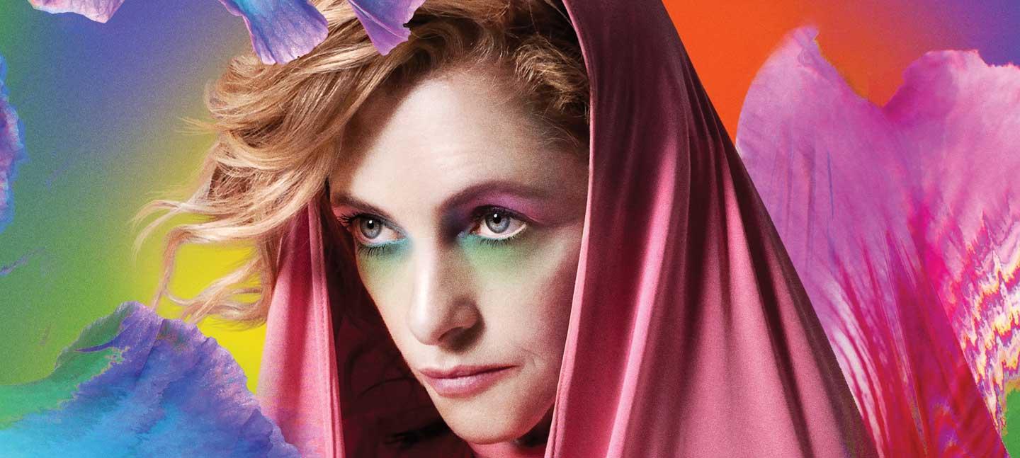 Alison Goldfrapp close-up photo headshot with the musician wearing a pink hood and abstract multi-coloured make-up