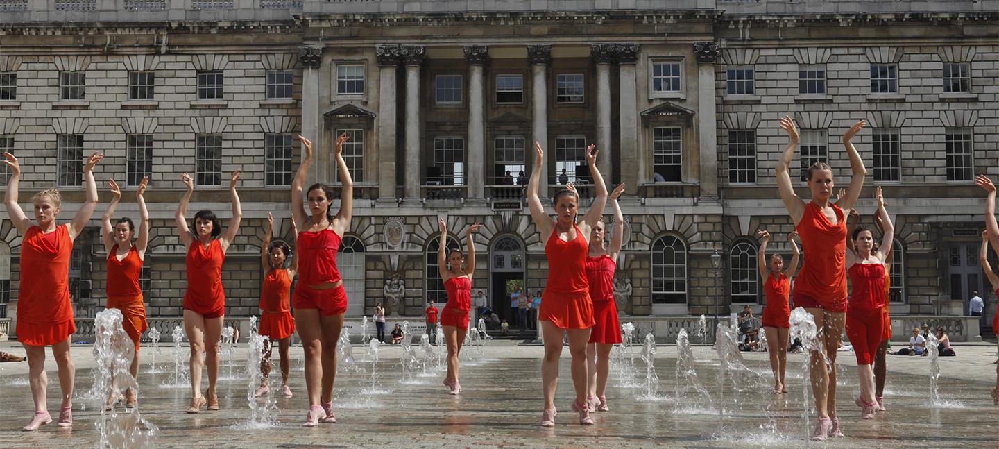 Dancers dressed in red perform amongst the fountains in the courtyard at Somerset House