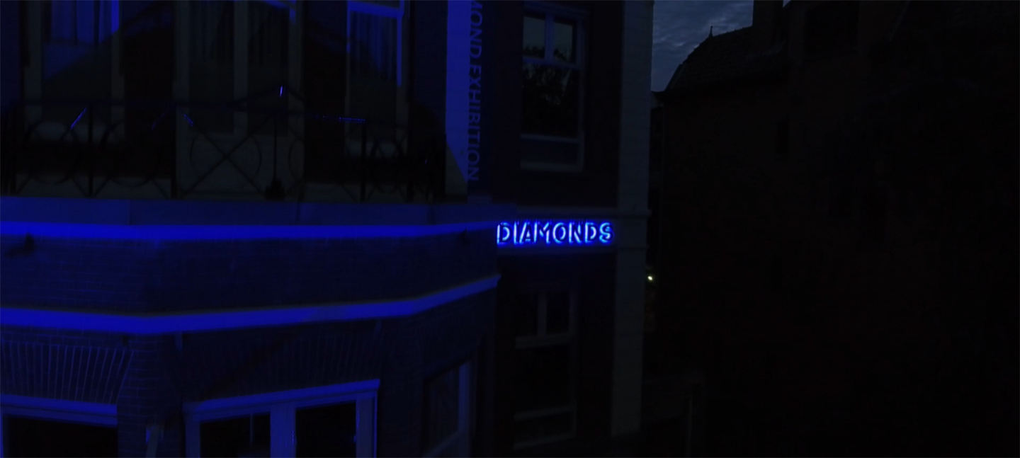 A still from Gerda Paliušytė's film. It depicts a blue neon sign on a building that says 'diamonds'