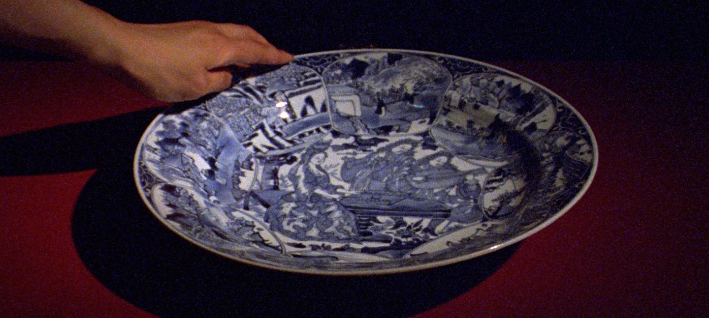 A still from Occidente by Ana Vaz. It shows a hand holding a china plate.
