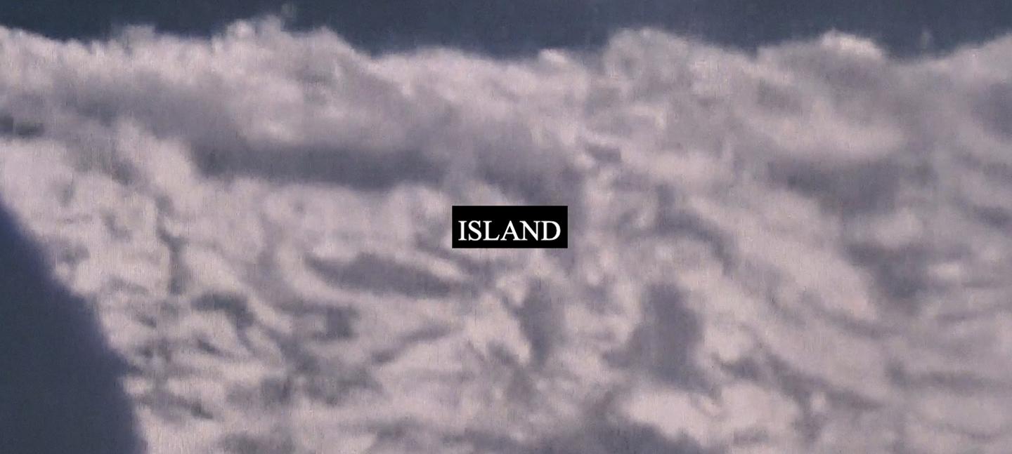 A still from Laura Grace Ford & Sam William's film ISLAND. It shows a fuzzy cloud-like substance with word ISLAND printed on it