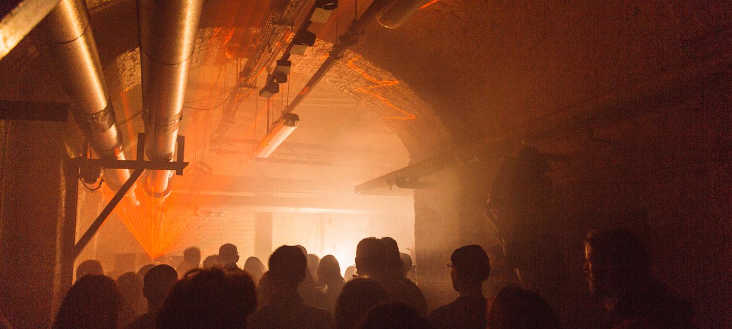 Crowd of people at a lice music event with lasers and smoke in The Deadhouse at Somerset House