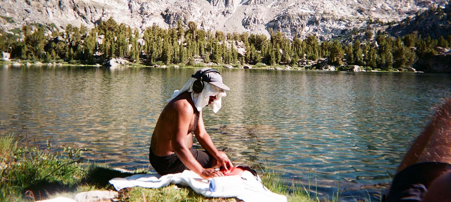 A man sits by a body of water with headphones on