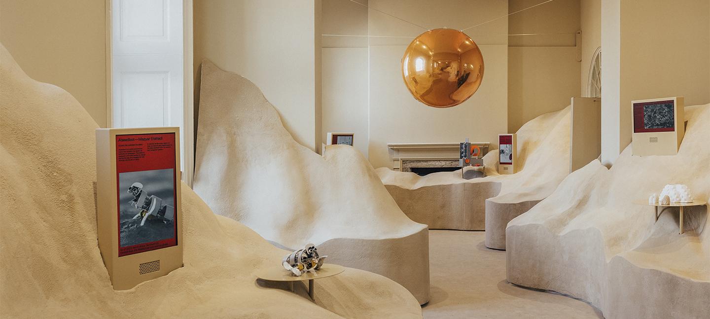 An installation view of Dubai's pavilion at London Design Biennale 2023. Towers of sand are piled high in a room, with a pathway cutting through the middle. 