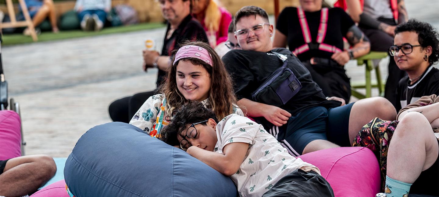 Some young people are lounging on beanbags in the courtyard and smiling.