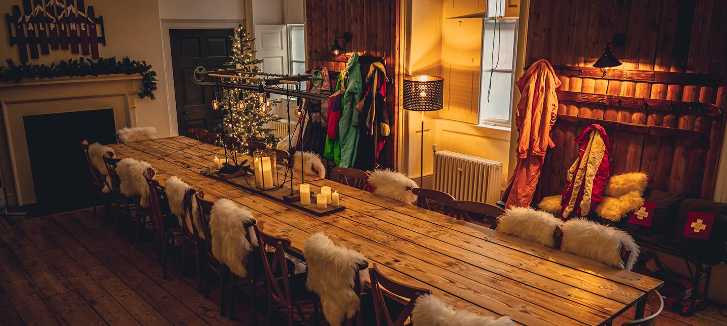 A long dining table in a cosy looking room with candles and fairy lights.