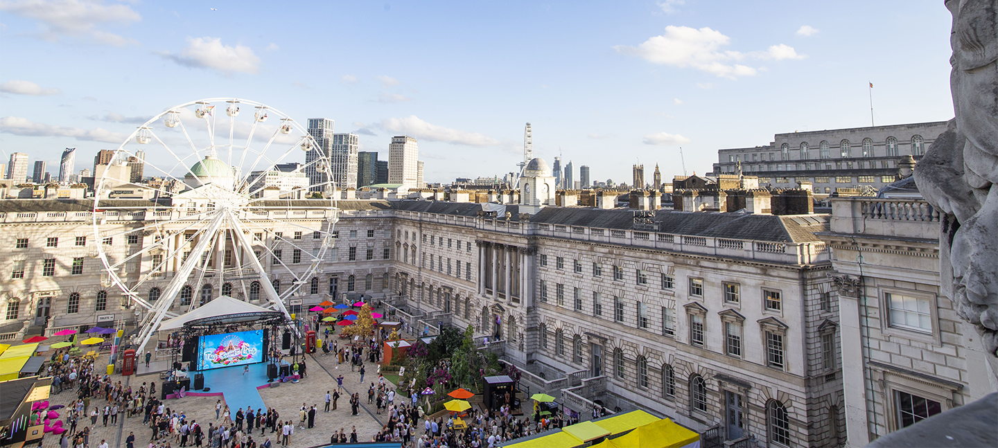 A photo of Somerset House's courtyard from the roof of the Courtauld (North Wing building). At the centre of the courtyard ia giant ferris wheel and crowds are gathering in the courtyard.