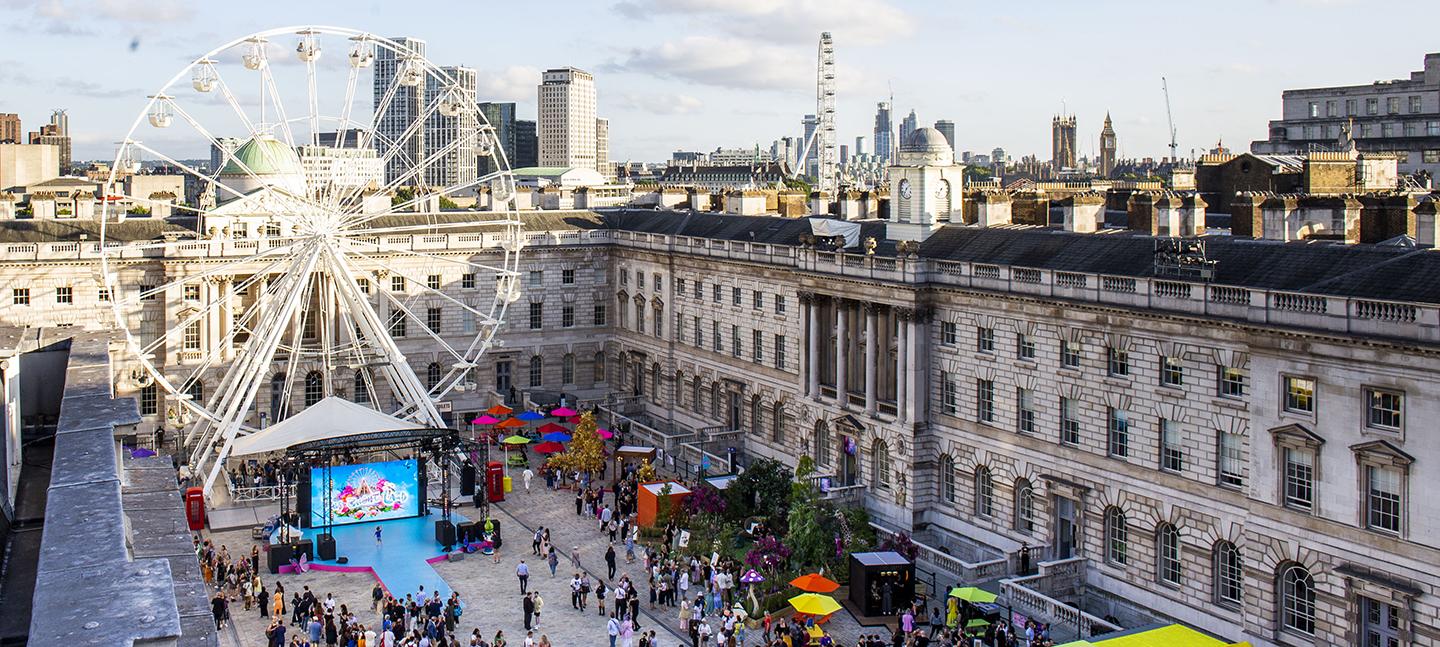 An aerial photo of Somerset House's courtyard, taken by Chloe Hashemi. Below you can see a big ferris wheel, a stage, and crowds of people gathering. The skies are 