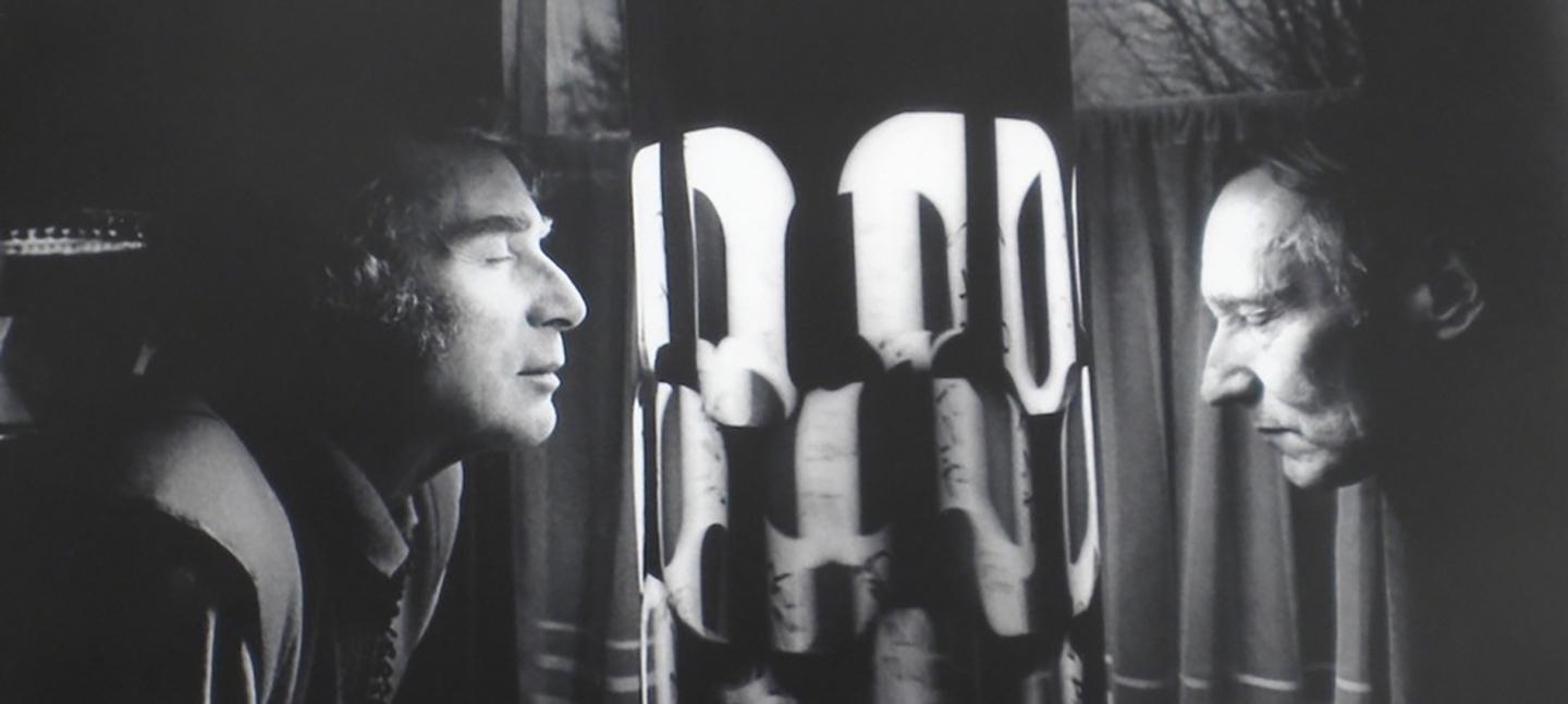 A black and white photo of two men looking at a light installation / dream machine