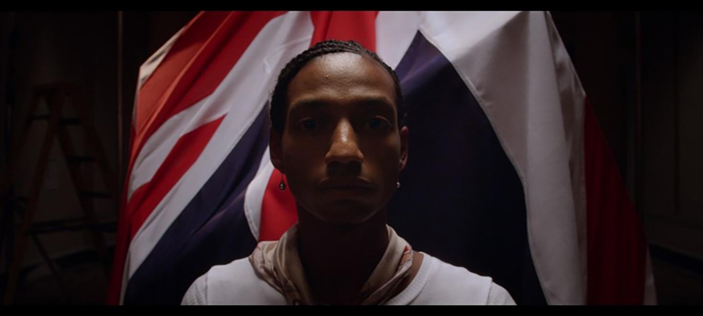 A still from Gareth Pugh's film 'Soul of a Movement'. It shows a person stood infront of a Union Jack flag.