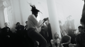 A black and white photo of Rowdy SS performing at AGM a few years ago. He is dancing, as a crowd of people watch on, enjoying themselves.