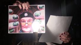 Someone holding up a photo of a woman in a headband and glasses to the camera, with a lit light bulb in front.