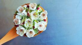 An aerial view of a tart that has been tastefully decorated with white edible flowers and herbs.