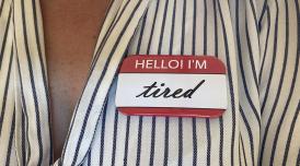 A photo of a person's upper chest, with a sticker on it that reads 'Hello! I'm tired'
