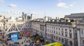 A photo of Somerset House's courtyard from the roof of the Courtauld (North Wing building). At the centre of the courtyard ia giant ferris wheel and crowds are gathering in the courtyard.