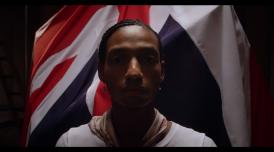 A still from Gareth Pugh's film 'Soul of a Movement'. It shows a person stood infront of a Union Jack flag.