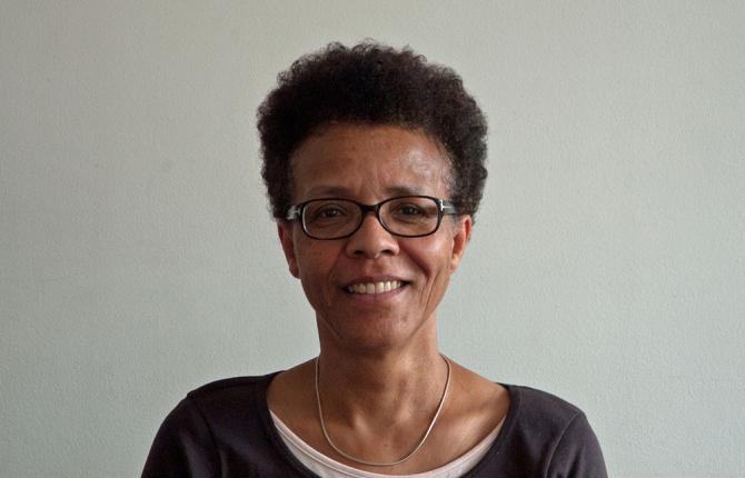 A photo of Gail Lewis. A Black woman wearing glasses with short cropped hair. Gail is looking directly to the camera and has a kind smile.